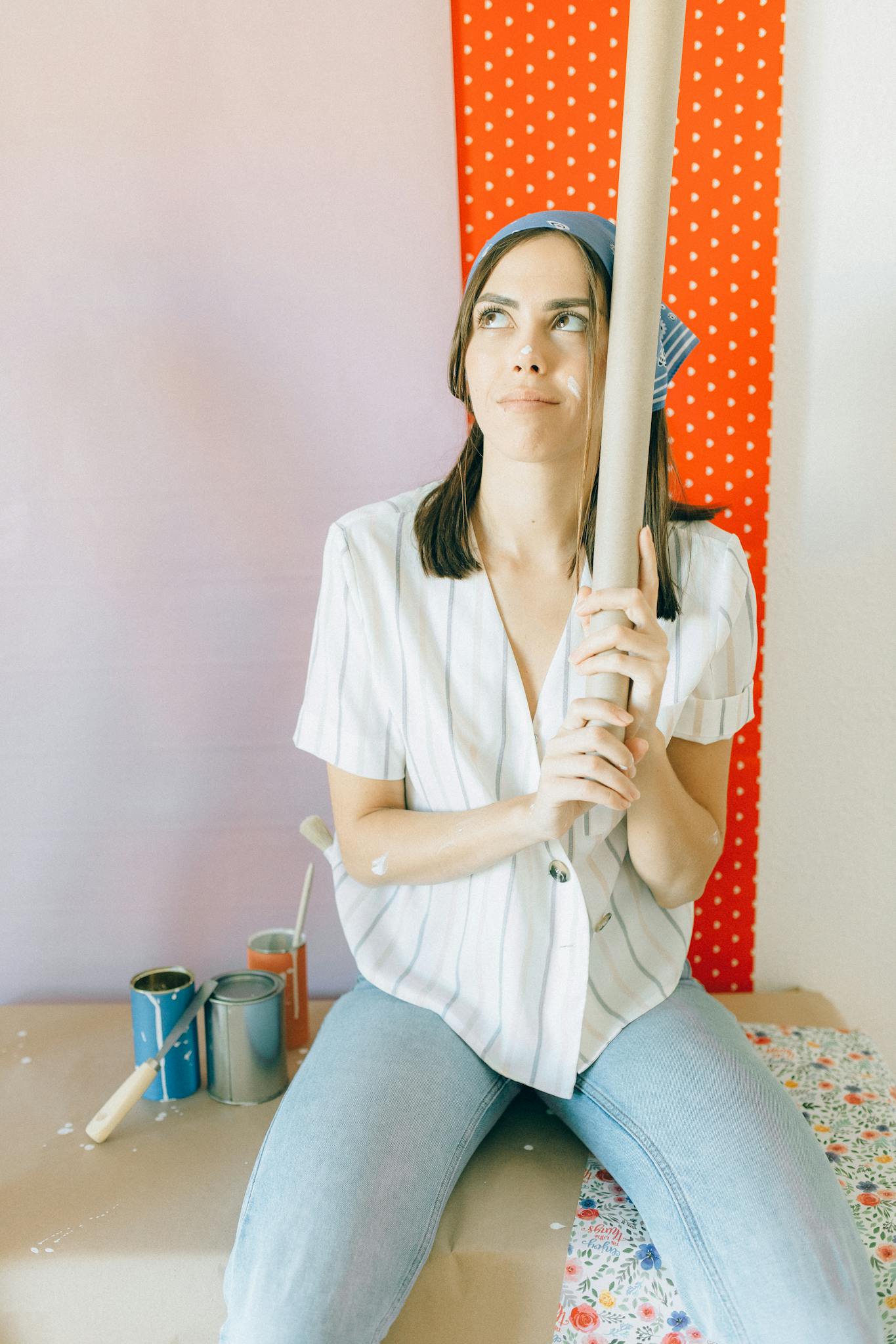 Woman holding wallpaper roll indoors, planning home design.