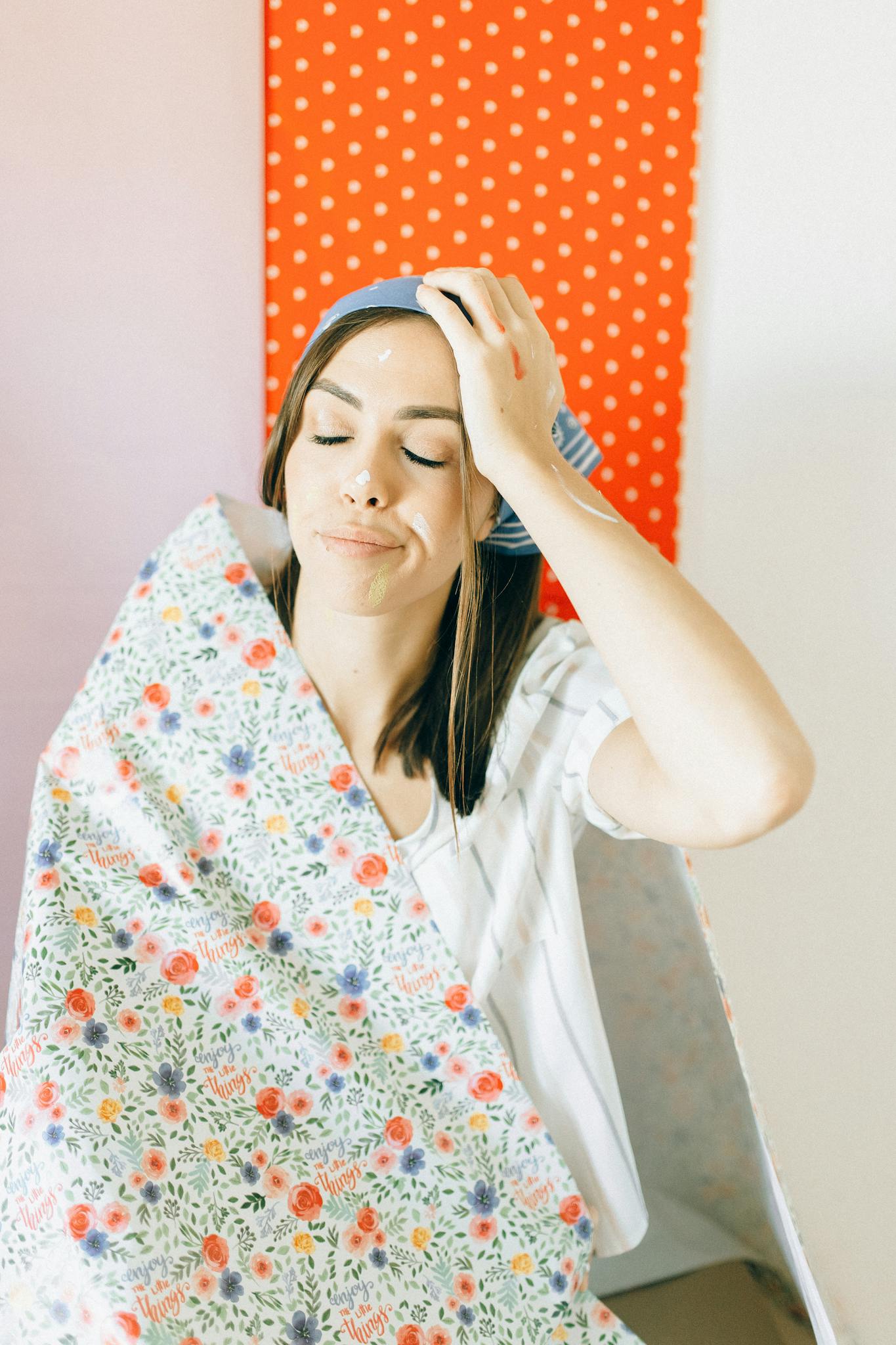 Young woman enjoying home decoration with floral and polka dot wallpaper.